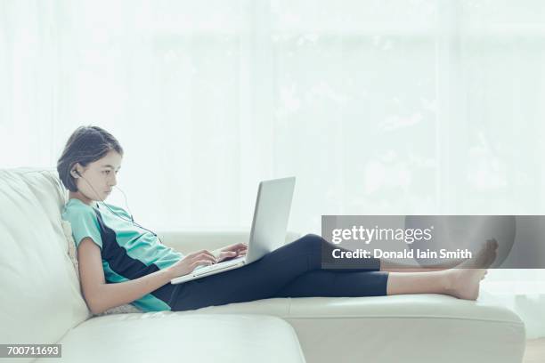 mixed race girl on sofa using laptop - barefoot girl stock pictures, royalty-free photos & images