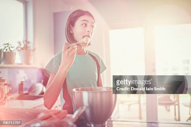 mixed race girl licking cookie dough on spoon - soft focus stock pictures, royalty-free photos & images