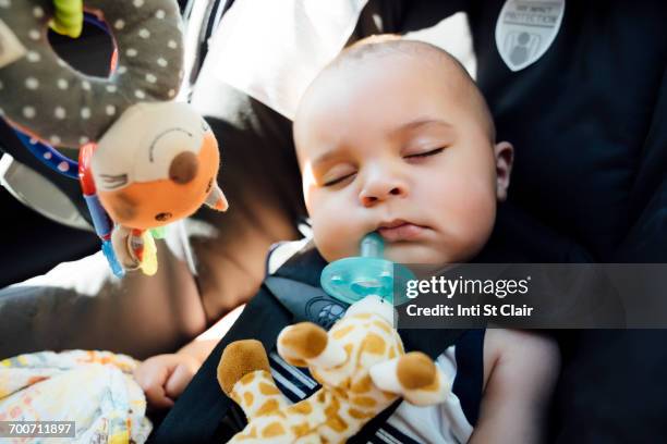 mixed race baby boy with pacifier sleeping in car seat - baby giraffe - fotografias e filmes do acervo