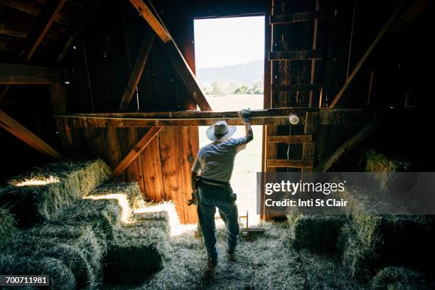 caucasian farmer resting in barn near bales of hay - barn stock pictures, royalty-free photos & images