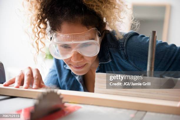 mixed race woman cutting wood with saw - protective eyewear 個照片及圖片檔