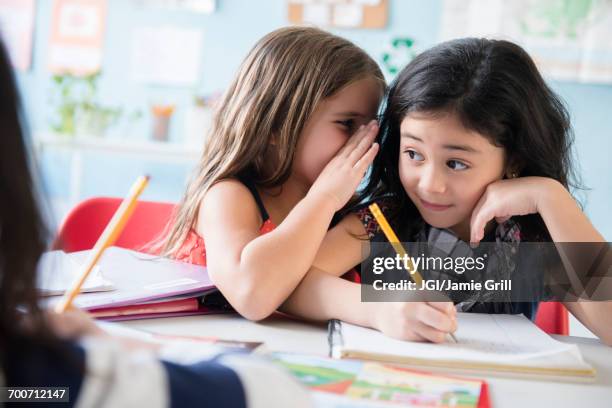 girl whispering to classmate in school - desonestidade imagens e fotografias de stock