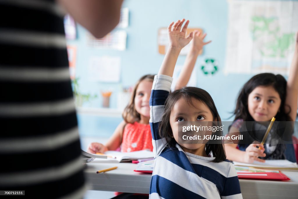 Girls raising hand for teacher in classroom