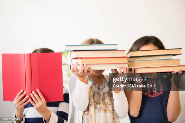 girls holding books in front of faces - hidden object stock pictures, royalty-free photos & images