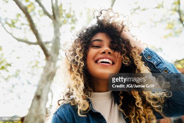 smiling mixed race woman with hand in hair - beauty curl stock pictures, royalty-free photos & images