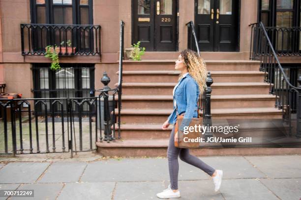 mixed race woman walking on city sidewalk - mixed race woman stock-fotos und bilder