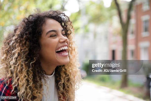 mixed race woman laughing in city - candid curly hair stock pictures, royalty-free photos & images