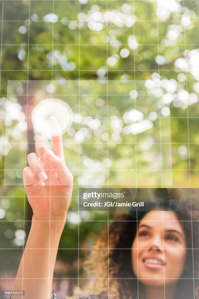 Mixed Race woman pointing to virtual screen outdoors