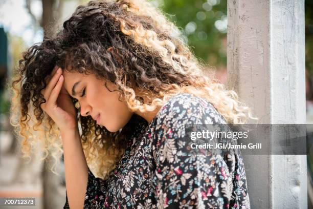 mixed race woman rubbing forehead - mal di testa foto e immagini stock