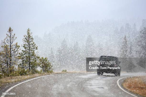 car driving on curving road in snow - usa cars stock-fotos und bilder