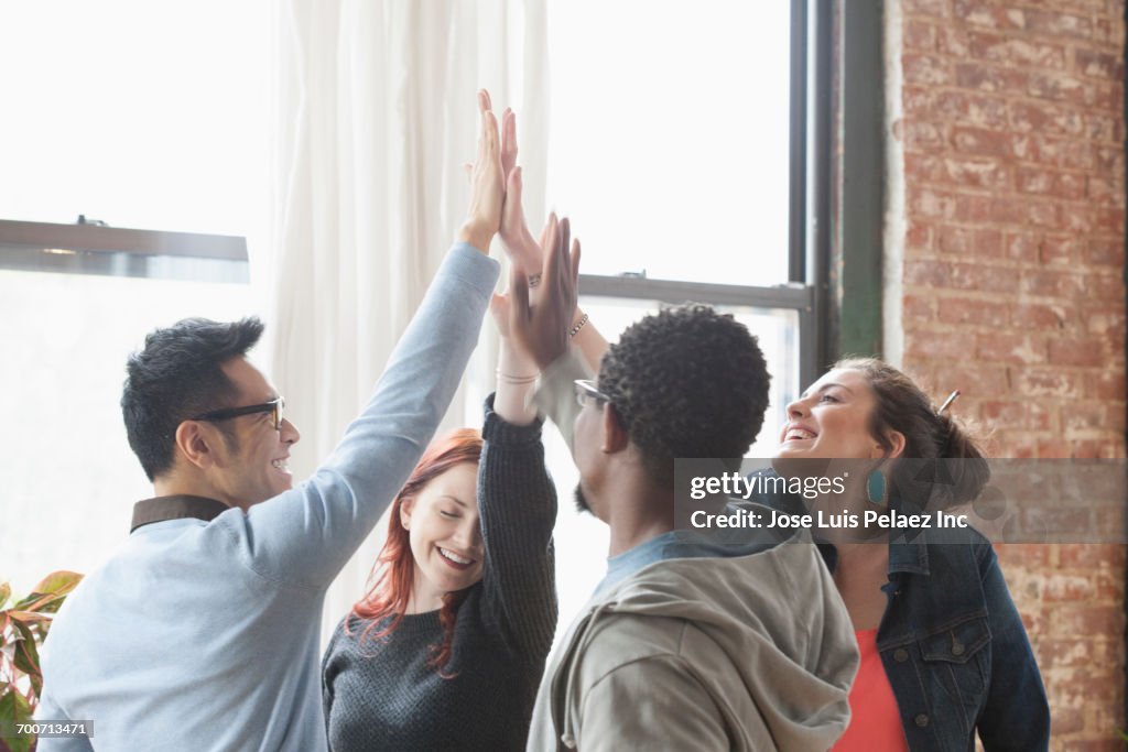 Business people high-fiving in office