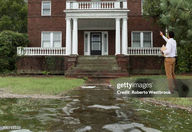 black insurance adjuster examining flooding damage to house - wasserschaden stock-fotos und bilder