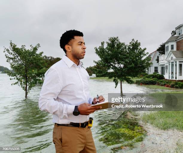 black insurance adjuster examining flooding damage to house - natural disaster photos et images de collection