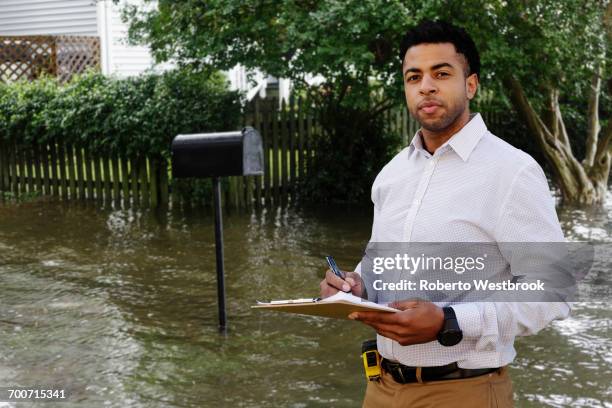 black insurance adjuster examining flooding damage to house - home disaster fotografías e imágenes de stock