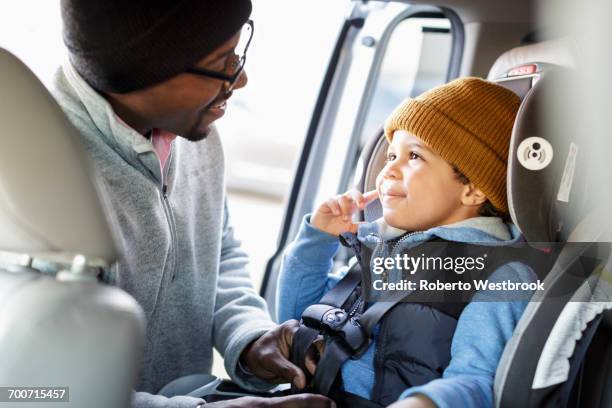 father buckling son in car seat - guy in car seat stockfoto's en -beelden