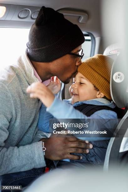 Father kissing son in car seat on forehead