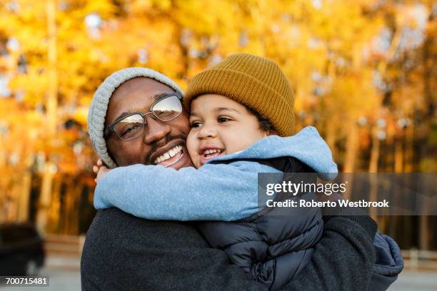 father and son hugging in park - modern manhood stock pictures, royalty-free photos & images