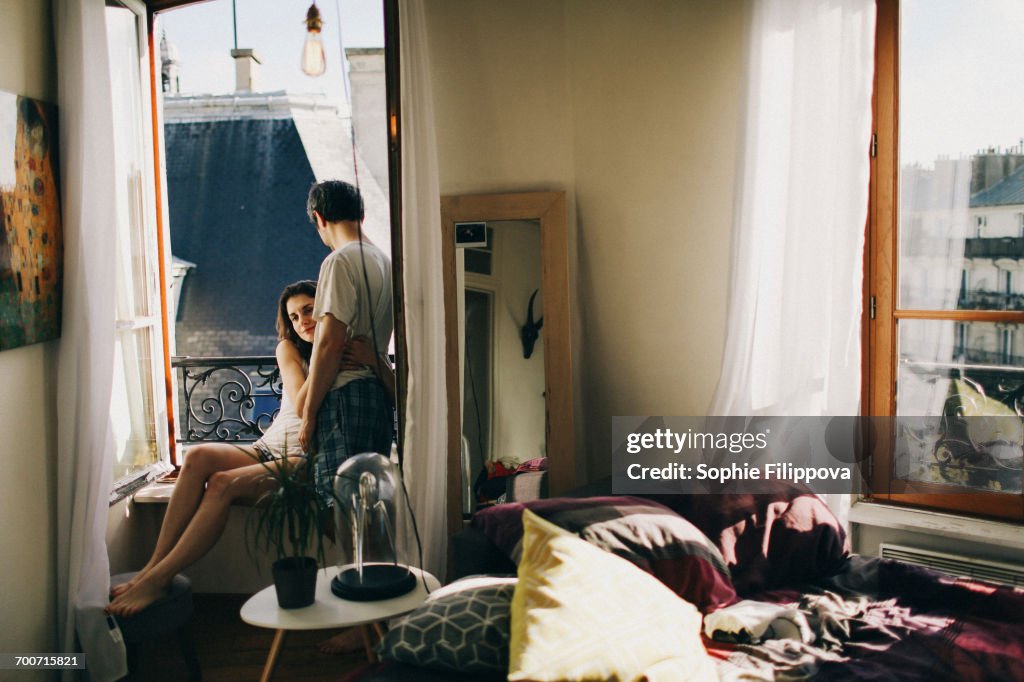 Caucasian couple hugging in apartment window