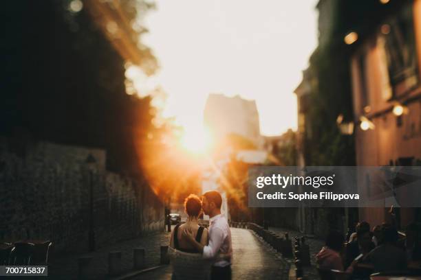 caucasian couple hugging in city street at sunset - paris millenials stock-fotos und bilder