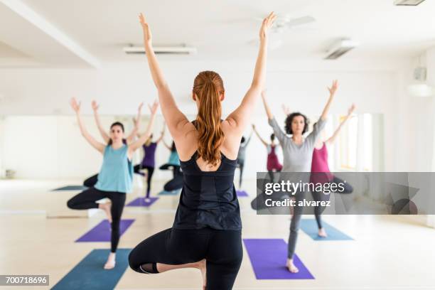 weibliche lehrer mit yoga-kurs in der turnhalle - rückentraining stock-fotos und bilder