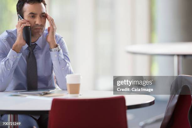 stressed businessman talking on cell phone at table - overdoing stock pictures, royalty-free photos & images