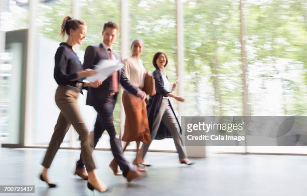 business people walking on the move in office lobby - flouté photos et images de collection