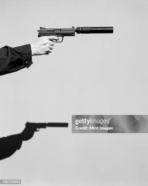 detail of man aiming high powered hand gun with silencer - revolver-with-silencer stock-fotos und bilder