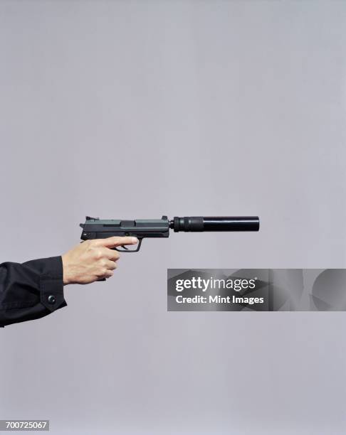 detail of man aiming high powered hand gun with silencer - hand holding gun stock pictures, royalty-free photos & images