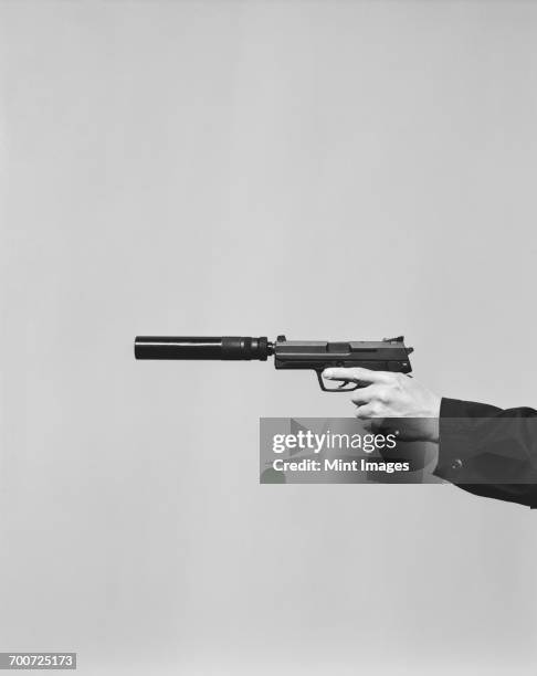 detail of man aiming high powered hand gun with silencer - revolver-with-silencer stock-fotos und bilder