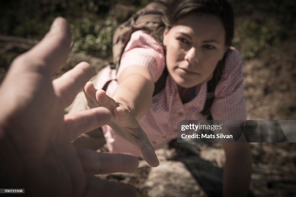 Female Rock Climber Reaching for Helping Hand