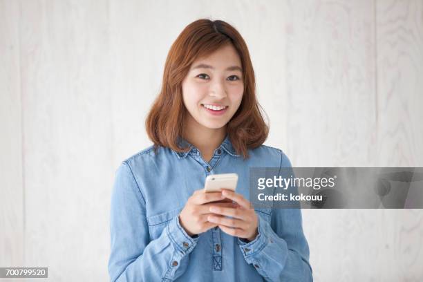 スマートフォンを持つ女性 - 若い女性 日本人 顔 ストックフォトと画像