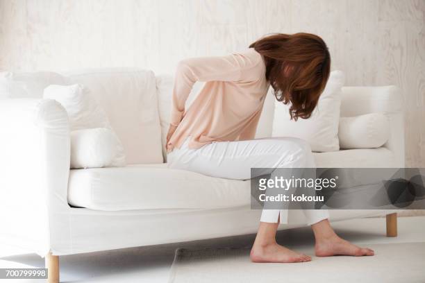 ソファに座っている女性 - 腰痛 ストックフォトと画像