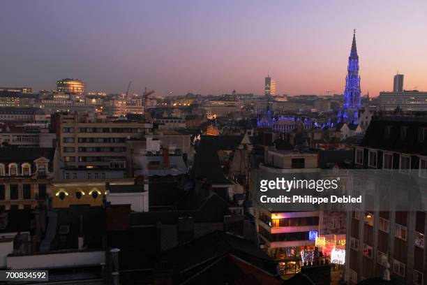 belgium, brussels, city skyline above the rooftops with town hall tower illuminated in blue - panorama brussels fotografías e imágenes de stock