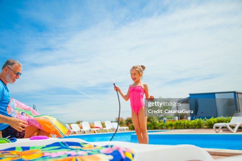 Joyful Daughter And Father Pumping A Water Wheel Toy On The Poolside