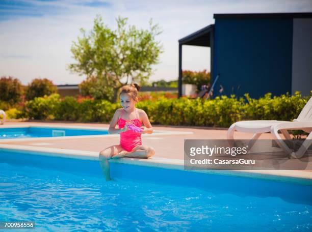 alegre menina sentada na beira da piscina - ankle deep in water - fotografias e filmes do acervo