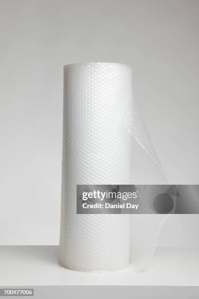 roll of bubble wrap against light grey background - bubble wrap stock pictures, royalty-free photos & images