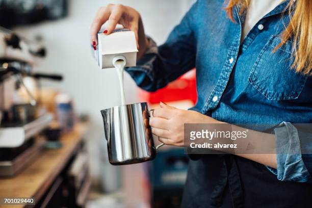 女性バリスタ カフェで水差しにミルクを注ぐ - 紙容器 ストックフォトと画像