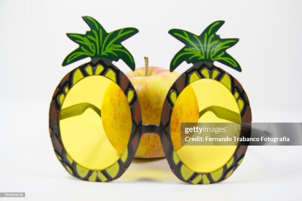 Apple behind a pineapple-shaped glasses