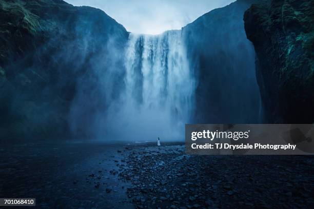 woman in long dress standing in front of a large misty waterfall, far away - majestic waterfall stock pictures, royalty-free photos & images