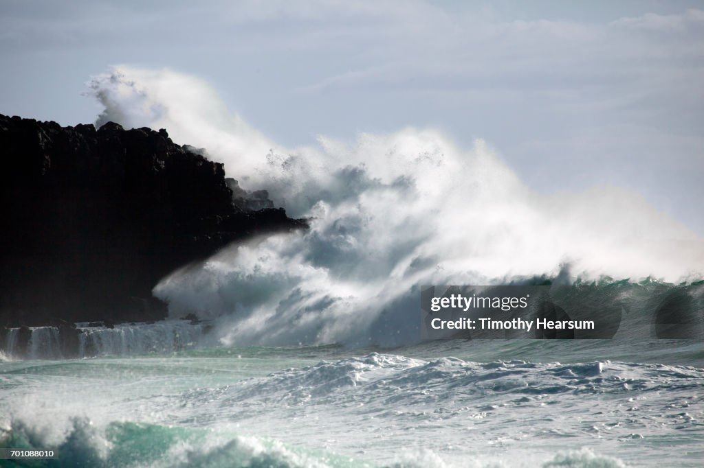 Large waves crash against cliff