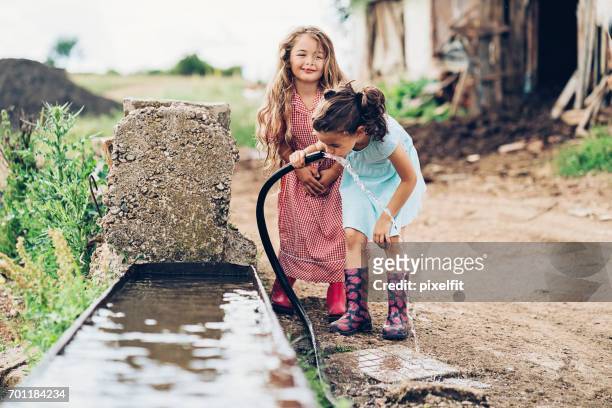 little girls drinking water from a hose - climate change kids stock pictures, royalty-free photos & images