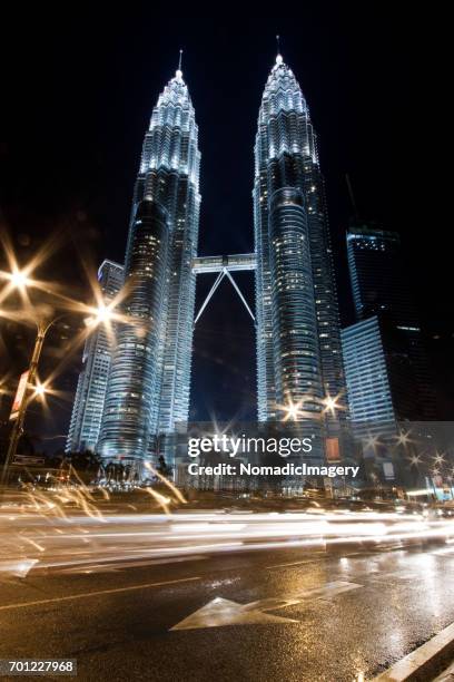 stunning towering petronas towers illuminated at night - skybridge petronas twin towers stock pictures, royalty-free photos & images