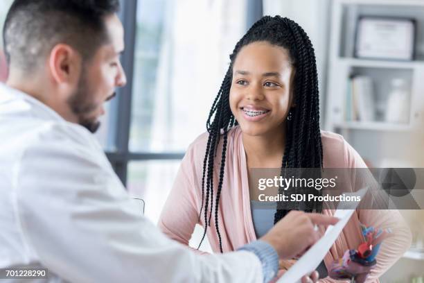 confident hispanic cardiologist discusses test results with patient - organe de reproduction masculin imagens e fotografias de stock