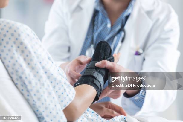 healthcare professional places brace on patient's arm - distenção imagens e fotografias de stock