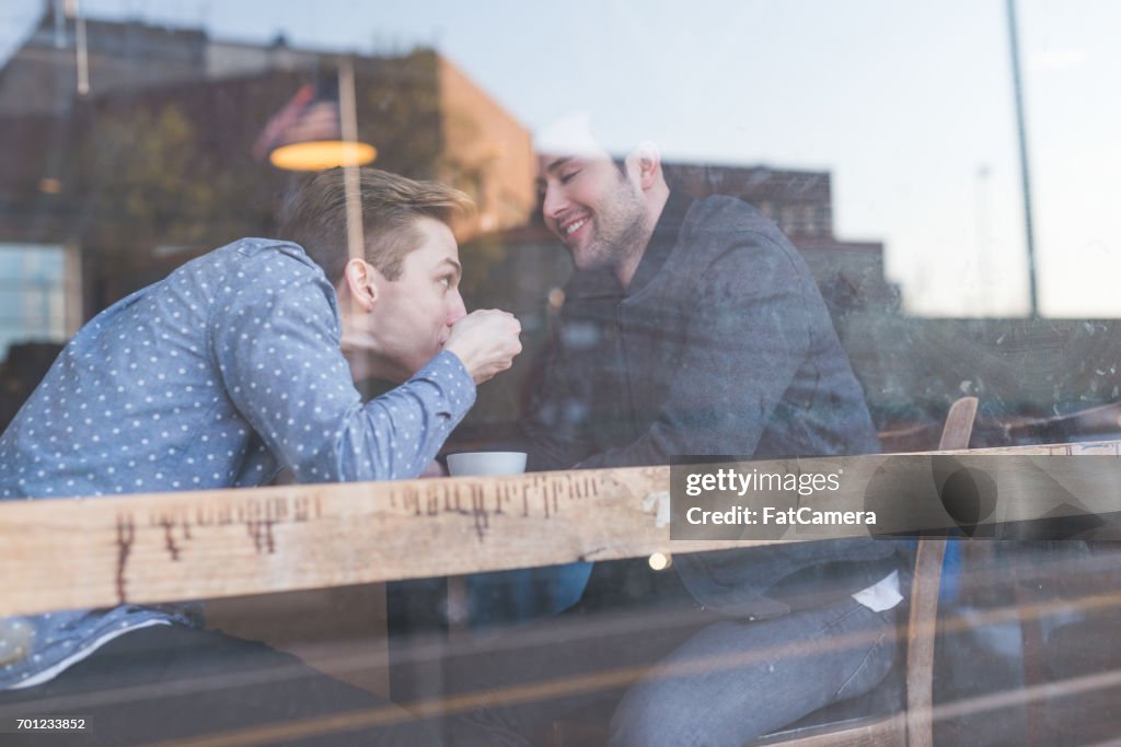 Geniet van de jonge mannelijke homo paar dranken en gesprek samen in een stedelijke koffiehuis