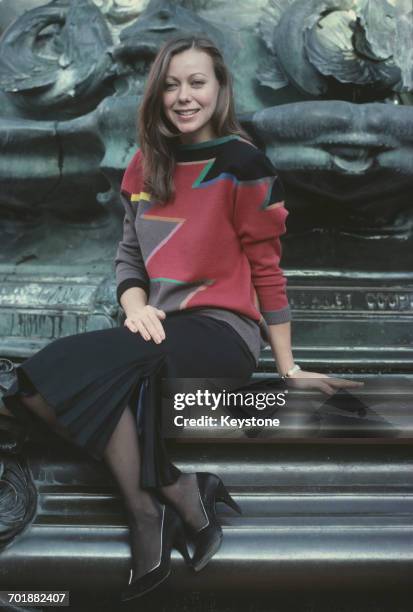 British actress Jenny Agutter sitting at the foot of the Shaftesbury Memorial Fountain in London, circa 1985.