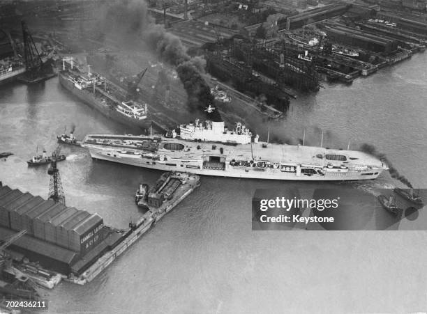 The Royal Navy Audacious-class fleet aircraft carrier HMS Ark Royal is maneuvered out by tugboats from the Cammell Laird shipyard in Birkenhead,...