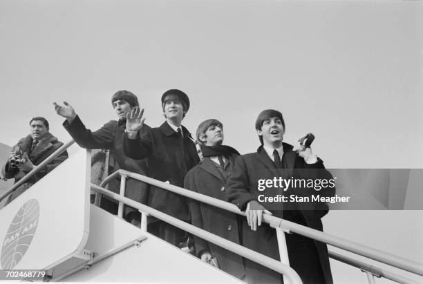 The Beatles at London Airport, en route to America, 13th February 1964. From left to right, a photographer, George Harrison, John Lennon, Ringo Starr...