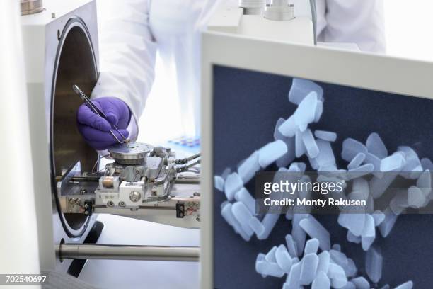 scientist placing sample in electron microscope with image of crystals in crystal engineering research laboratory - scanning electron microscope stock pictures, royalty-free photos & images
