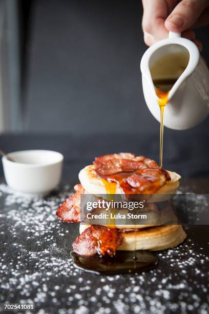 female hand pouring maple syrup over breakfast bacon crumpet on slate - crumpet fotografías e imágenes de stock